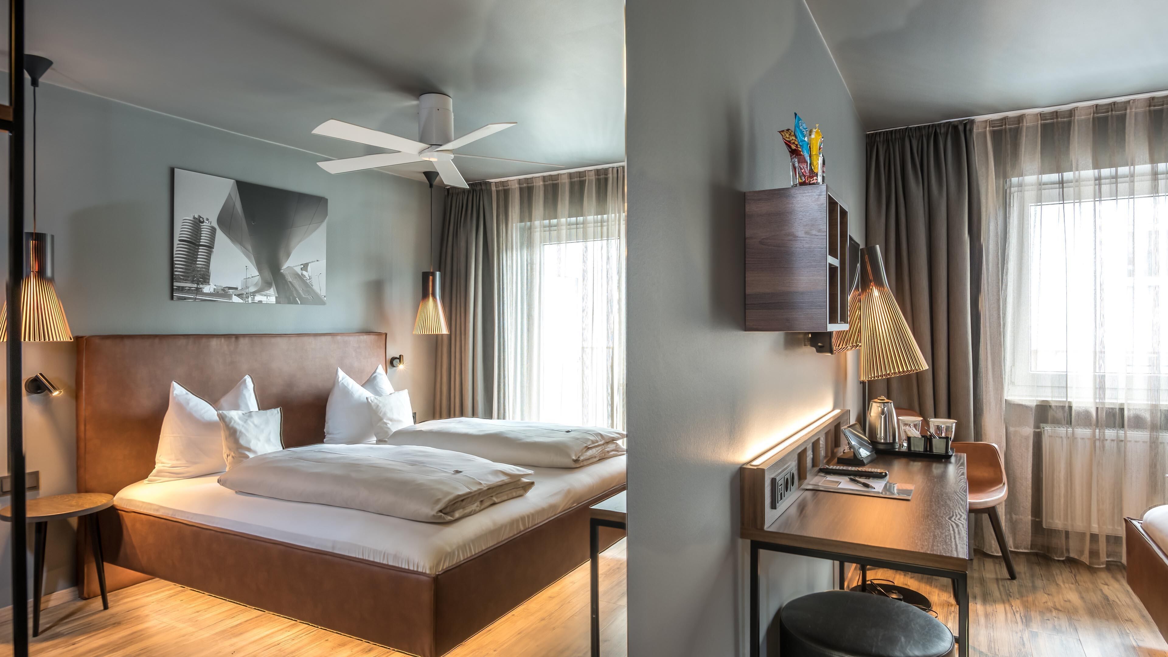 Une chambre d’hôtel comprenant un lit, une table de chevet, une lampe et un bureau avec une chaise.