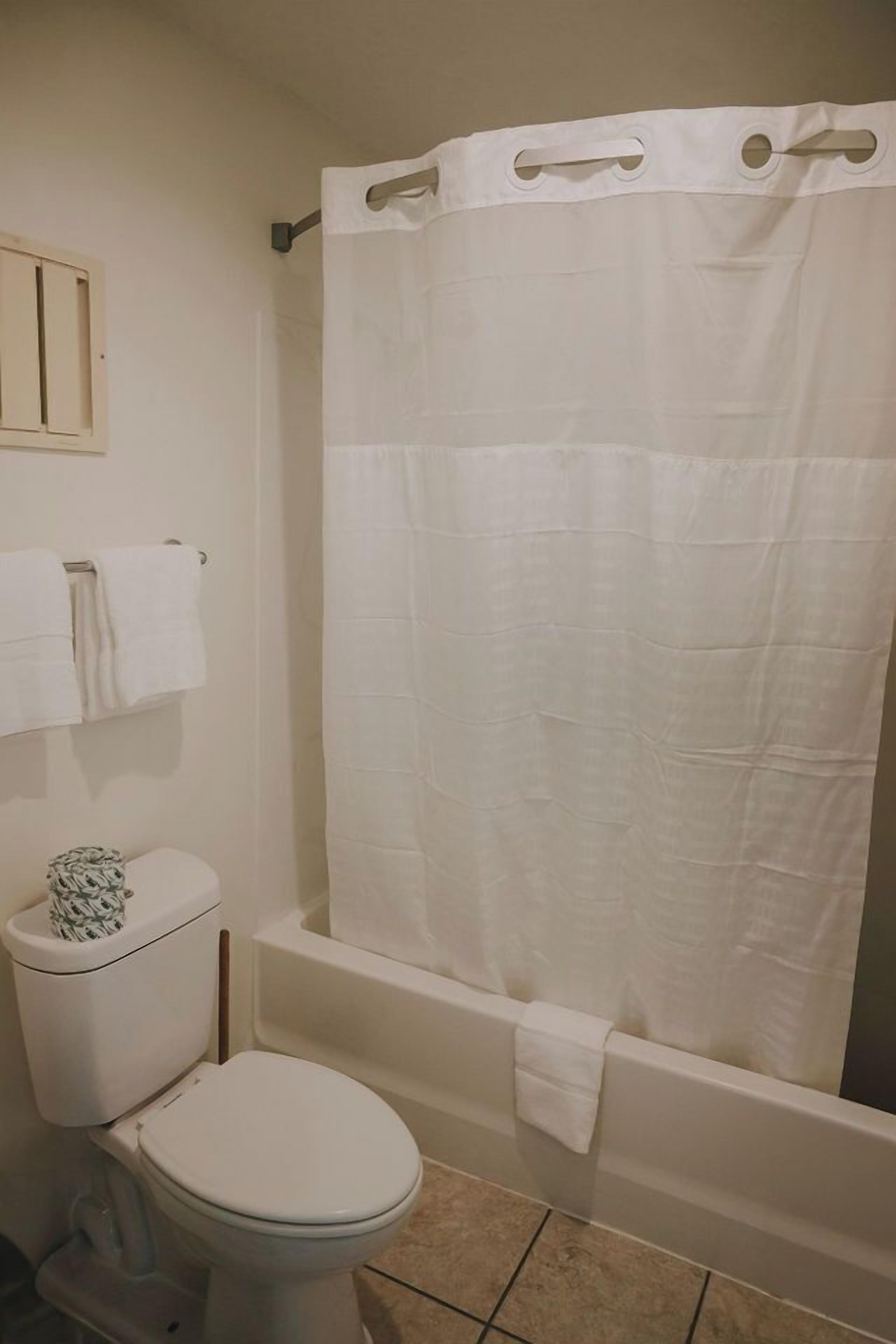 Une salle de bain équipée de toilettes, d’une baignoire et d’un rideau de douche.