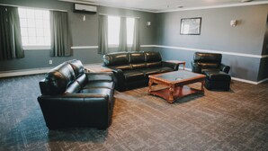 A room with a large window, a black leather sofa, a wooden coffee table, and a black leather armchair.