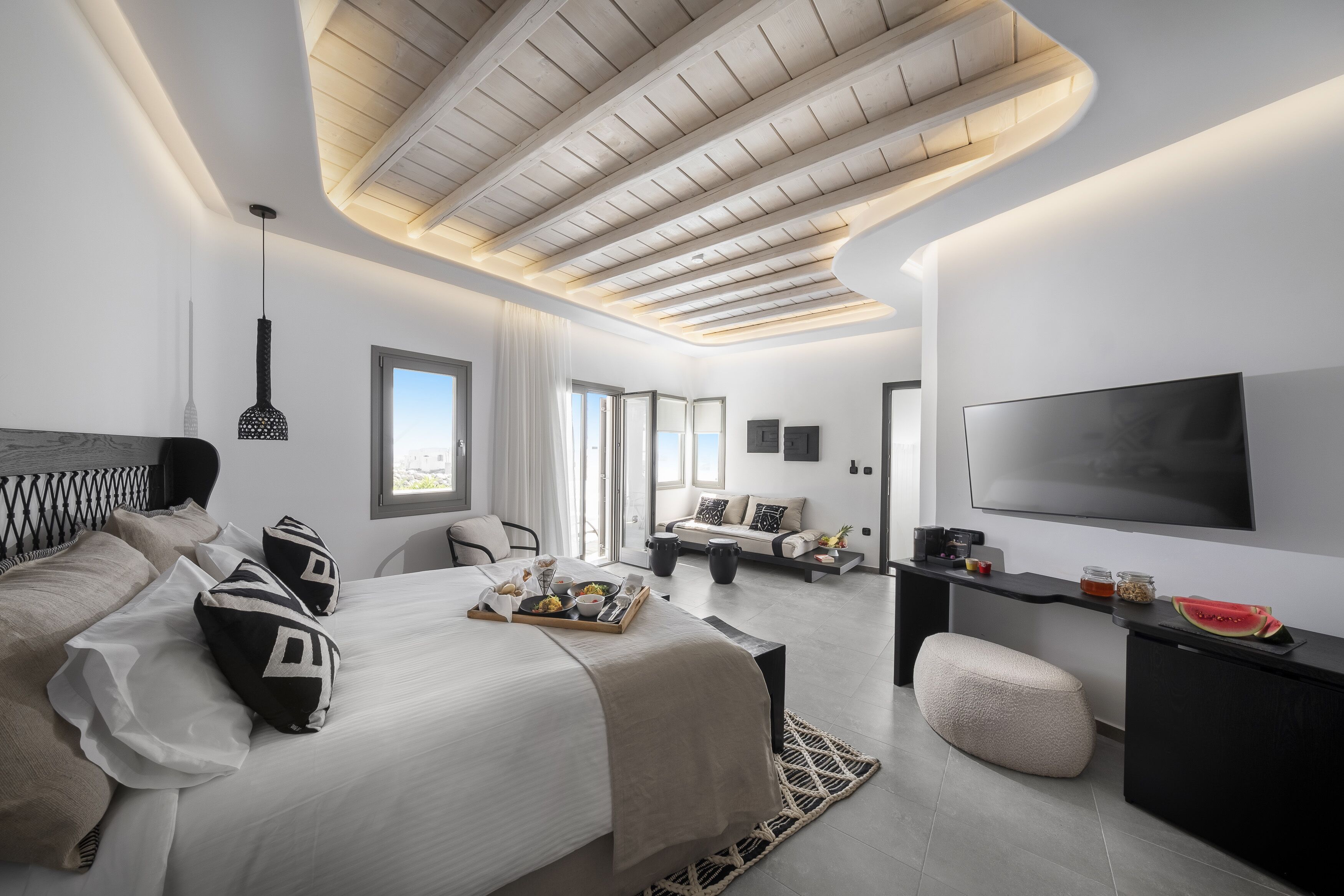 Quarto de hotel moderno com uma cama grande, uma escrivaninha, televisão e um espaço de refeições.