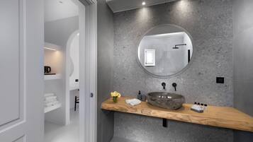 Une salle de bain moderne avec un miroir rond, un lavabo en pierre et un plan de toilette en bois.