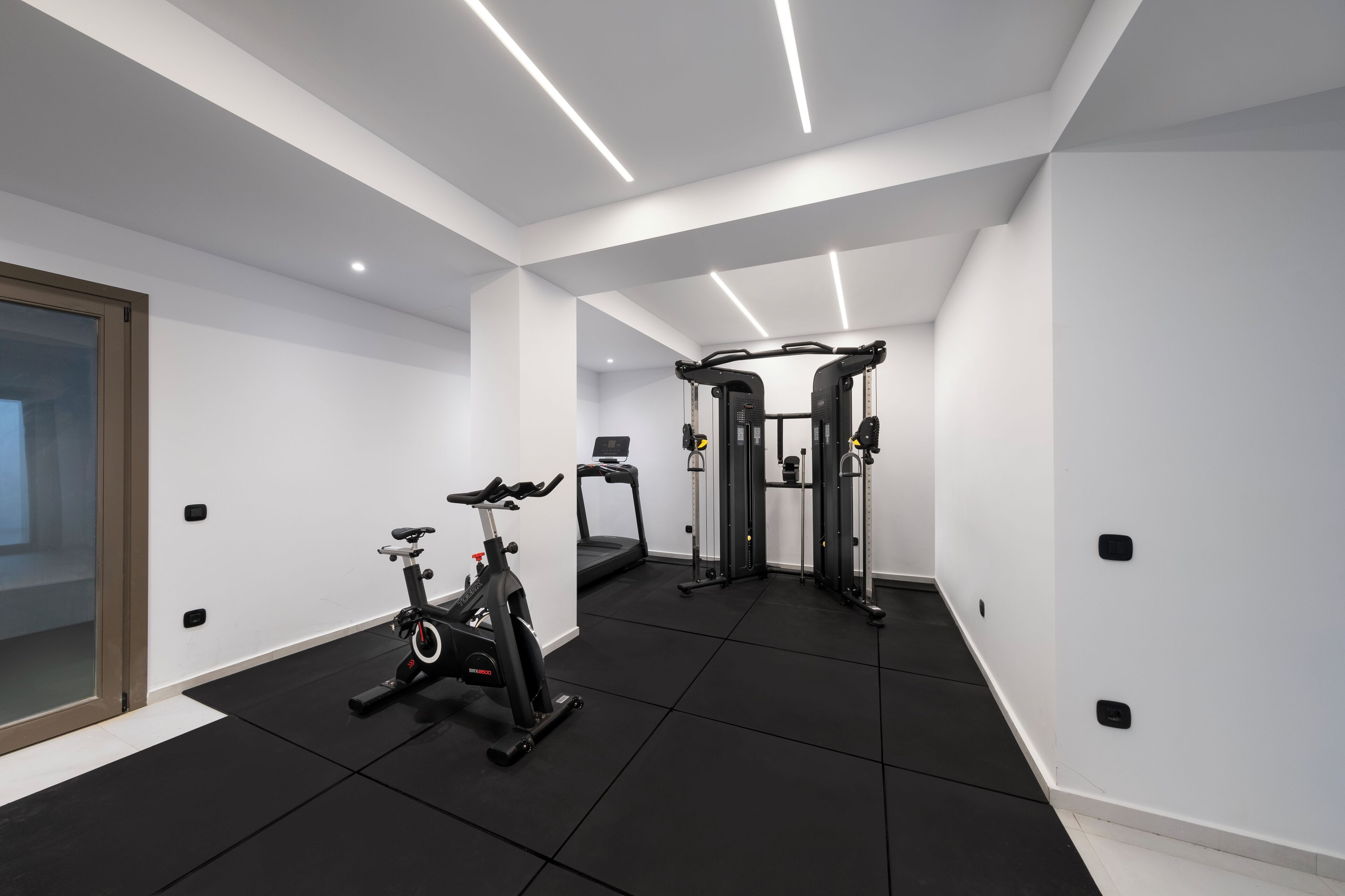Un gimnasio moderno con bicicleta estática, cinta de correr y equipo de levantamiento de pesas.