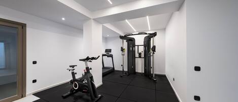 Un gimnasio moderno con bicicleta estática, cinta de correr y equipo de levantamiento de pesas.