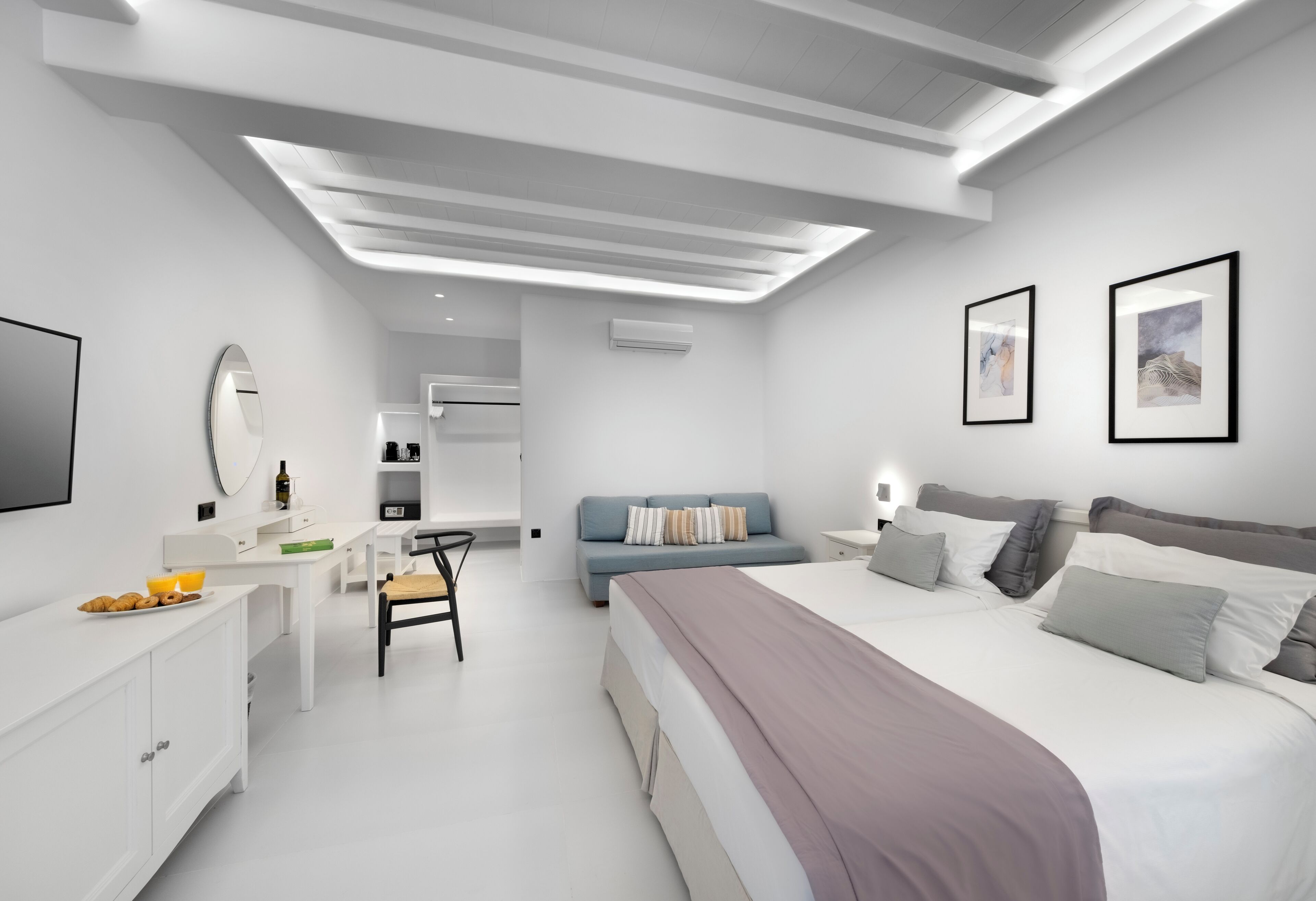 Un dormitorio moderno con una cama grande, un escritorio, una silla y una pequeña kitchenette.