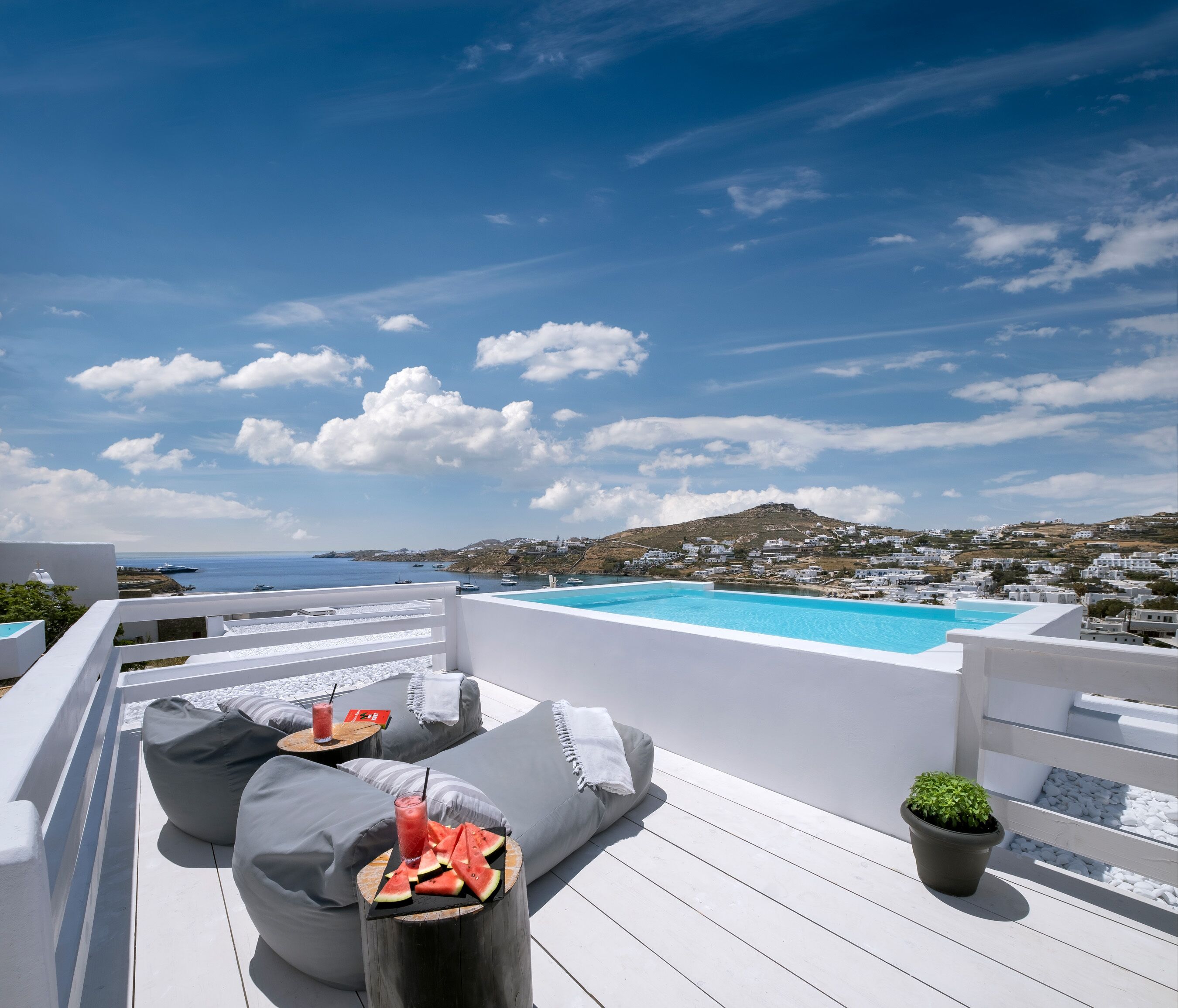 A rooftop terrace with a pool, seating area, and a view of the coastline.