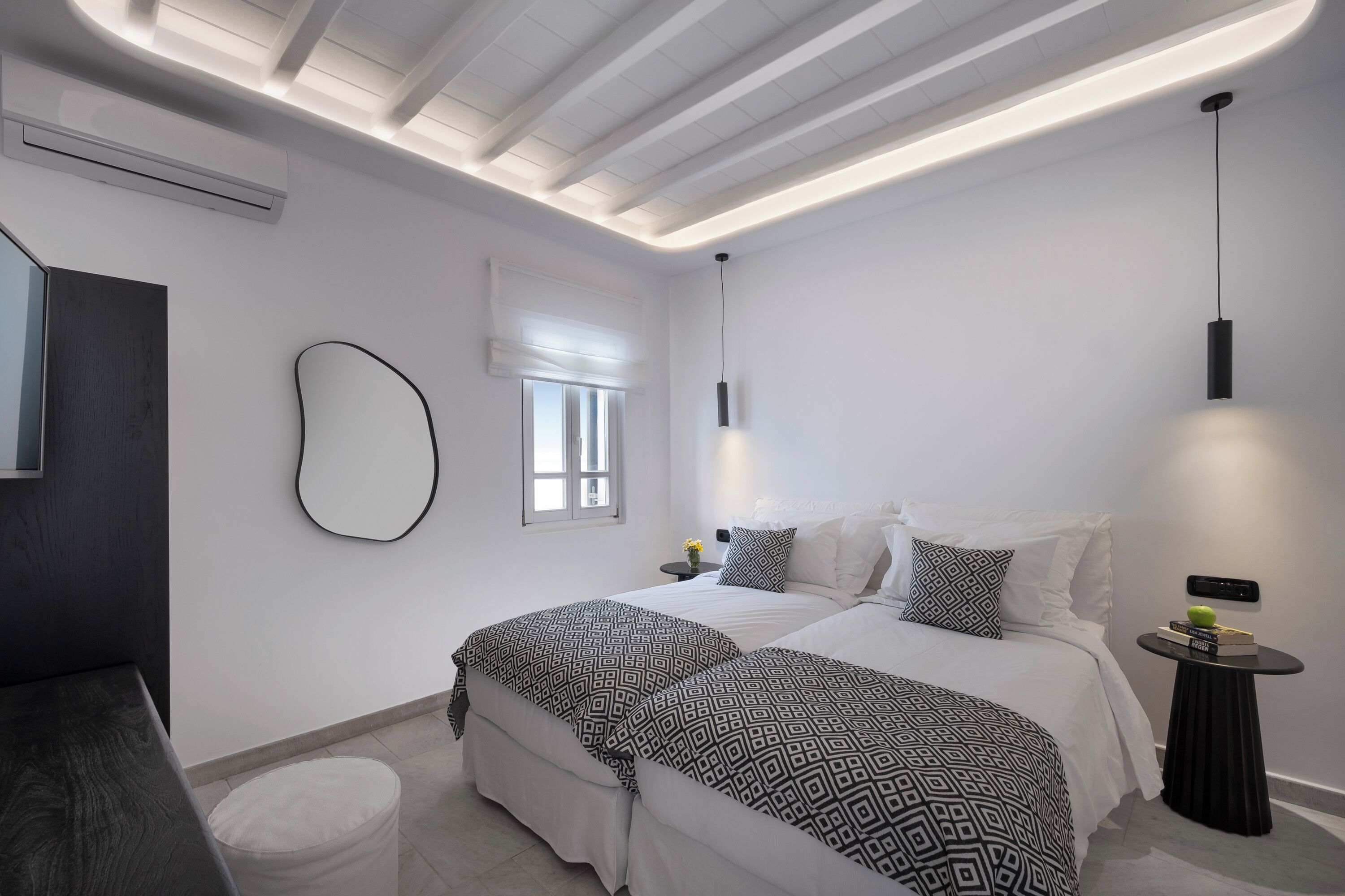 A modern bedroom with a bed, bedside tables, and a small round table.