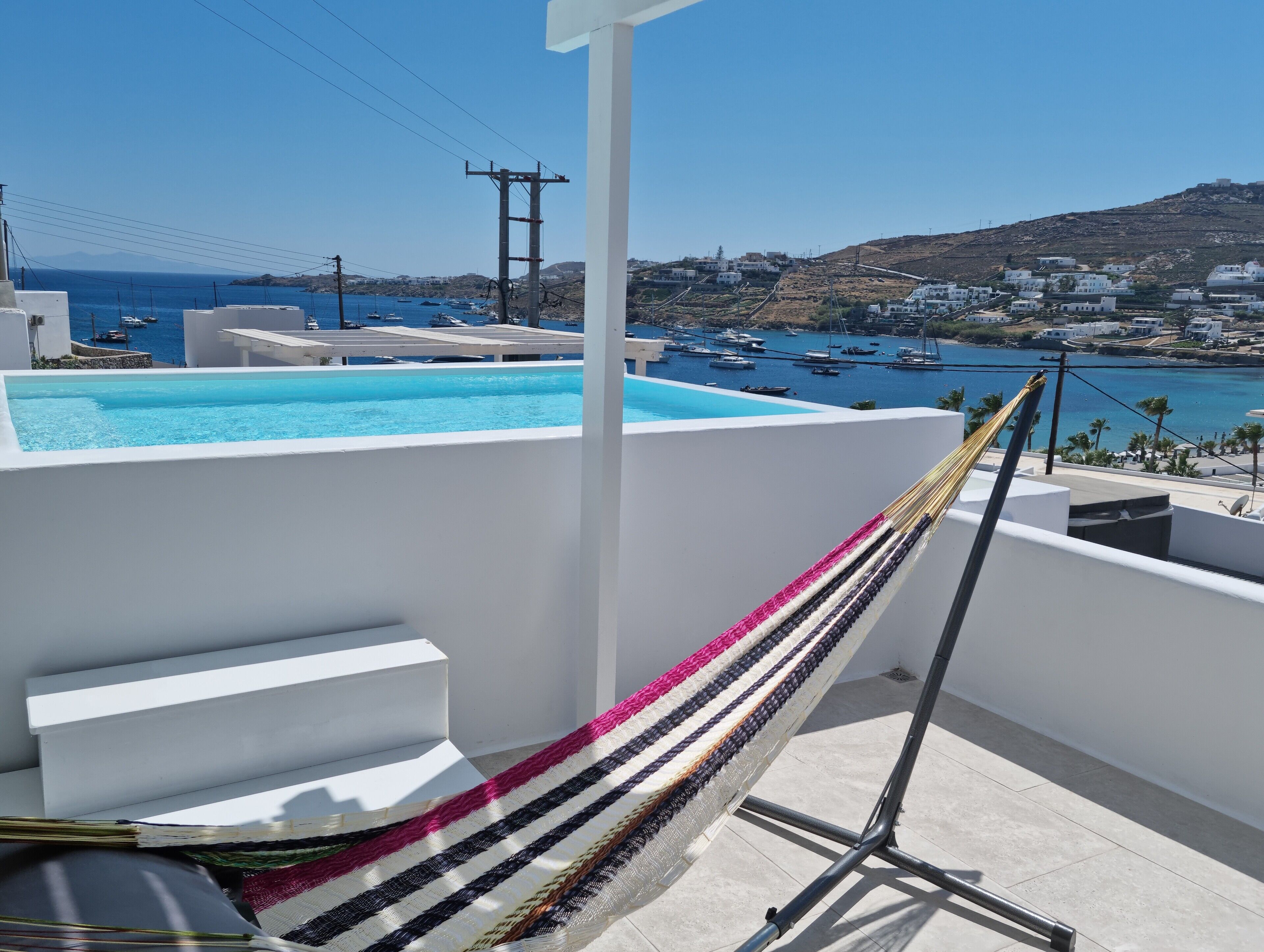 A balcony with a pool, a hammock, and a view of boats and houses.