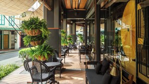 An outdoor cafe area with wicker furniture and hanging plants. - Duxton Reserve Singapore, Autograph Collection (Singapore)