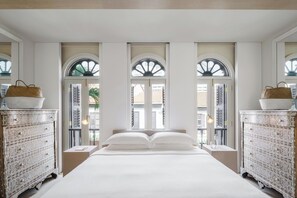 Un dormitorio con una cama grande, dos mesitas de noche y tres ventanas de arco.