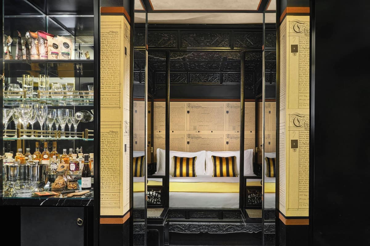 Une pièce comprenant un lit, une vitrine contenant des bouteilles et un mur avec du texte.