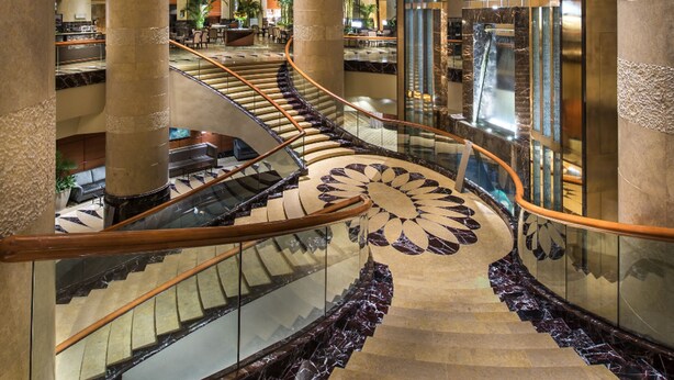 Un interior imponente con una escalera espiral central, amplias columnas y una moderna recepción.