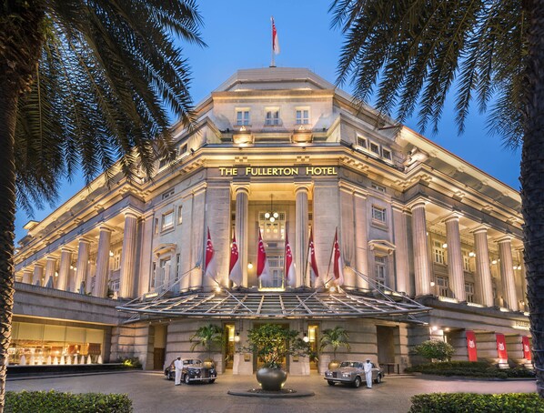 The Fullerton Hotel with classical architecture, multiple flags, and a well-lit entrance. - The Fullerton Hotel Singapore (Singapore)
