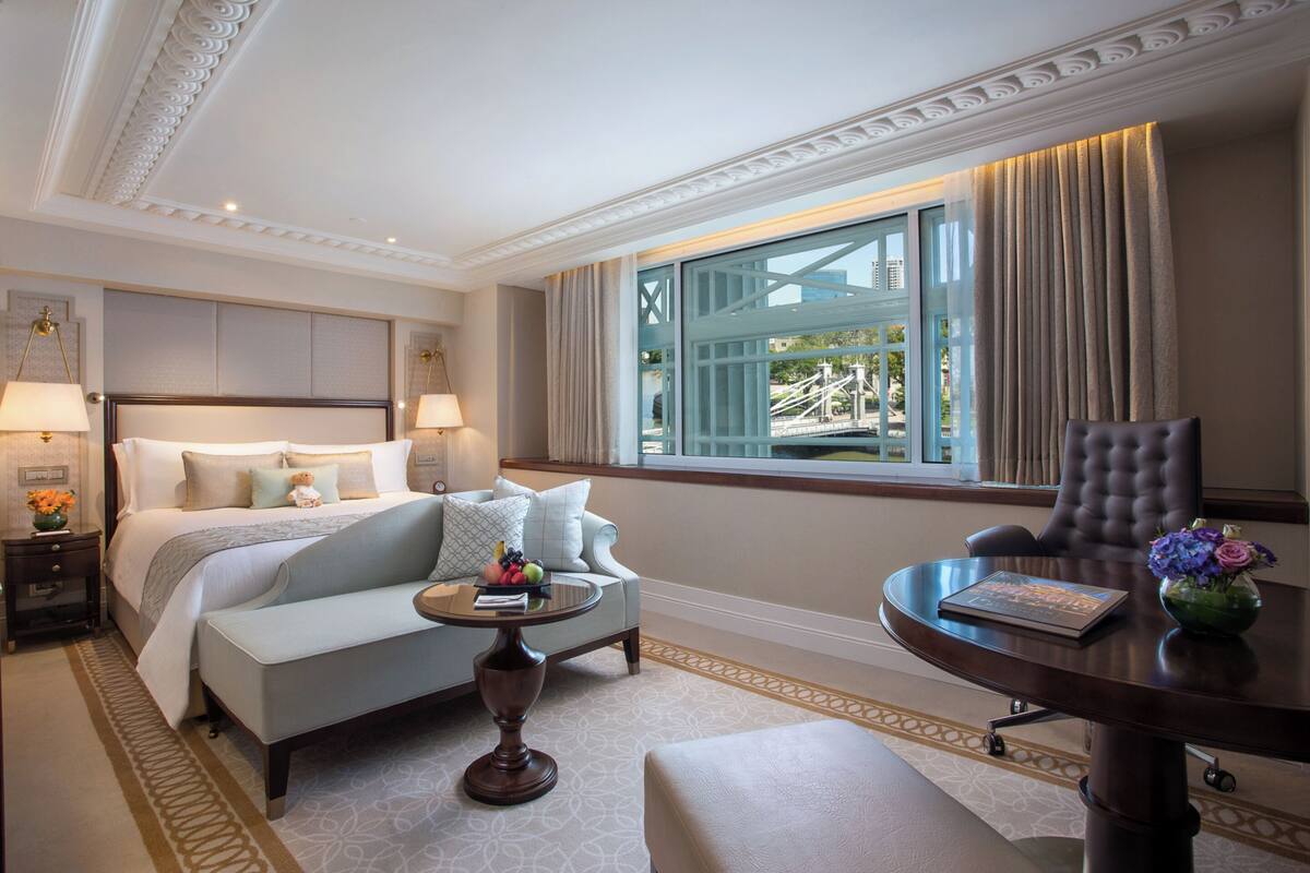 A hotel room with a bed, a sofa, a desk, and a view of the outdoors.