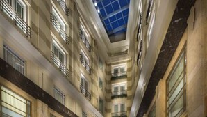Un vestíbulo espacioso con varias zonas de estar, una fuente central y un techo alto con tragaluces.