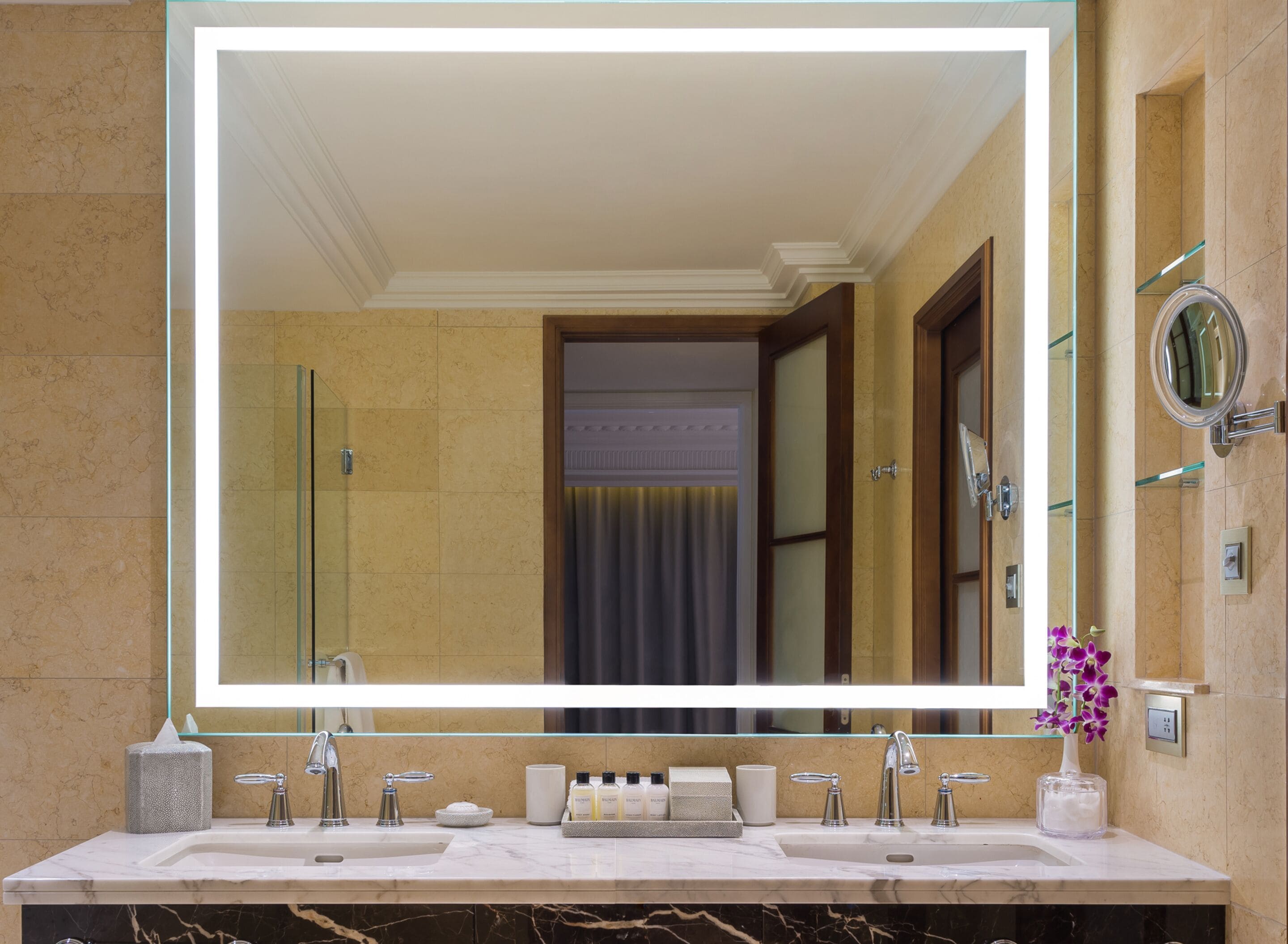 A bathroom with a large mirror, two sinks, and a vanity area with toiletries.