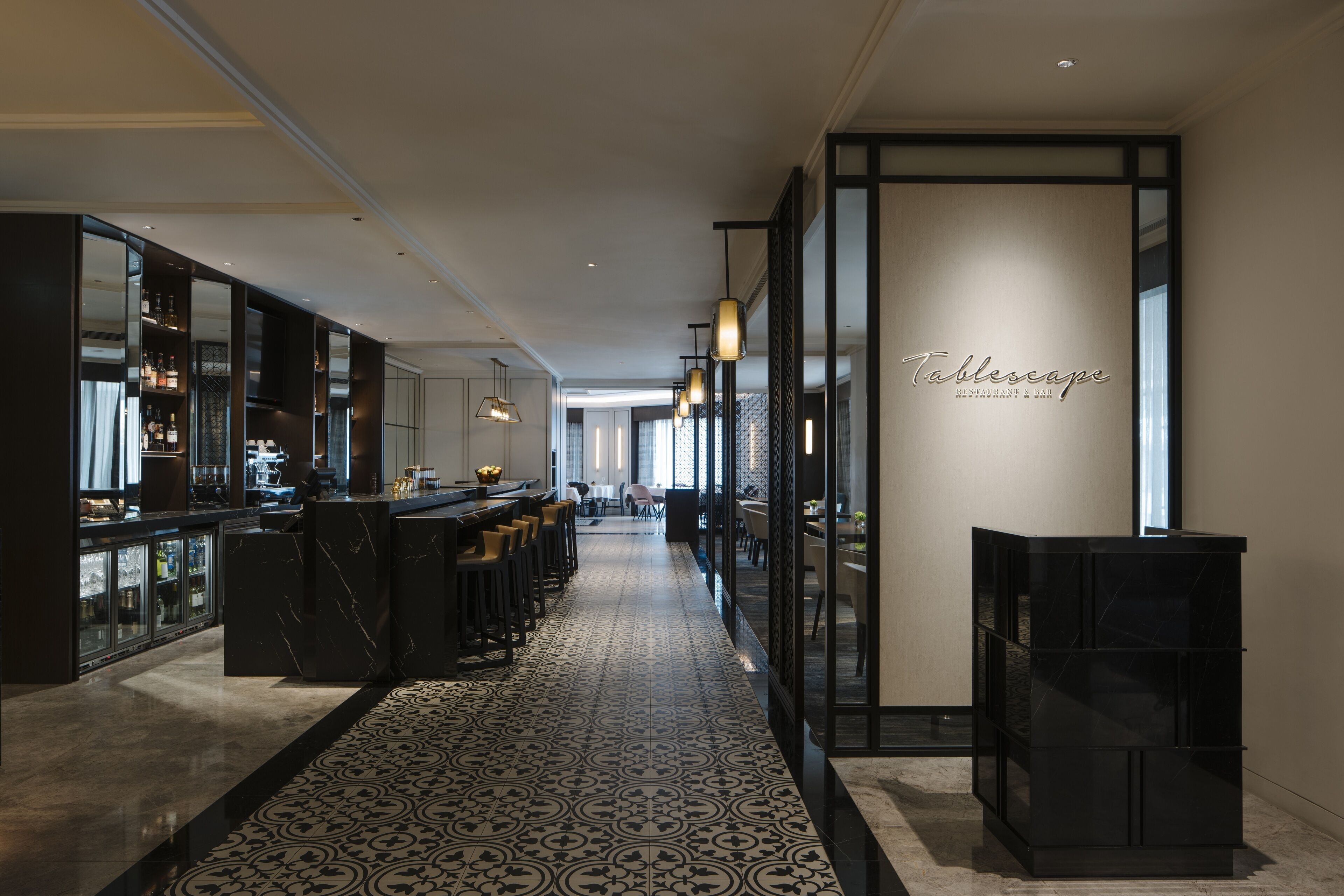 Un moderno vestíbulo de hotel con un largo pasillo, zona de bar y recepción.