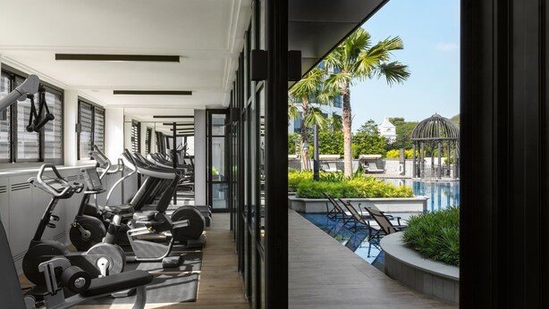 Un gimnasio moderno con equipo de cardio y vistas a una piscina y zona exterior.