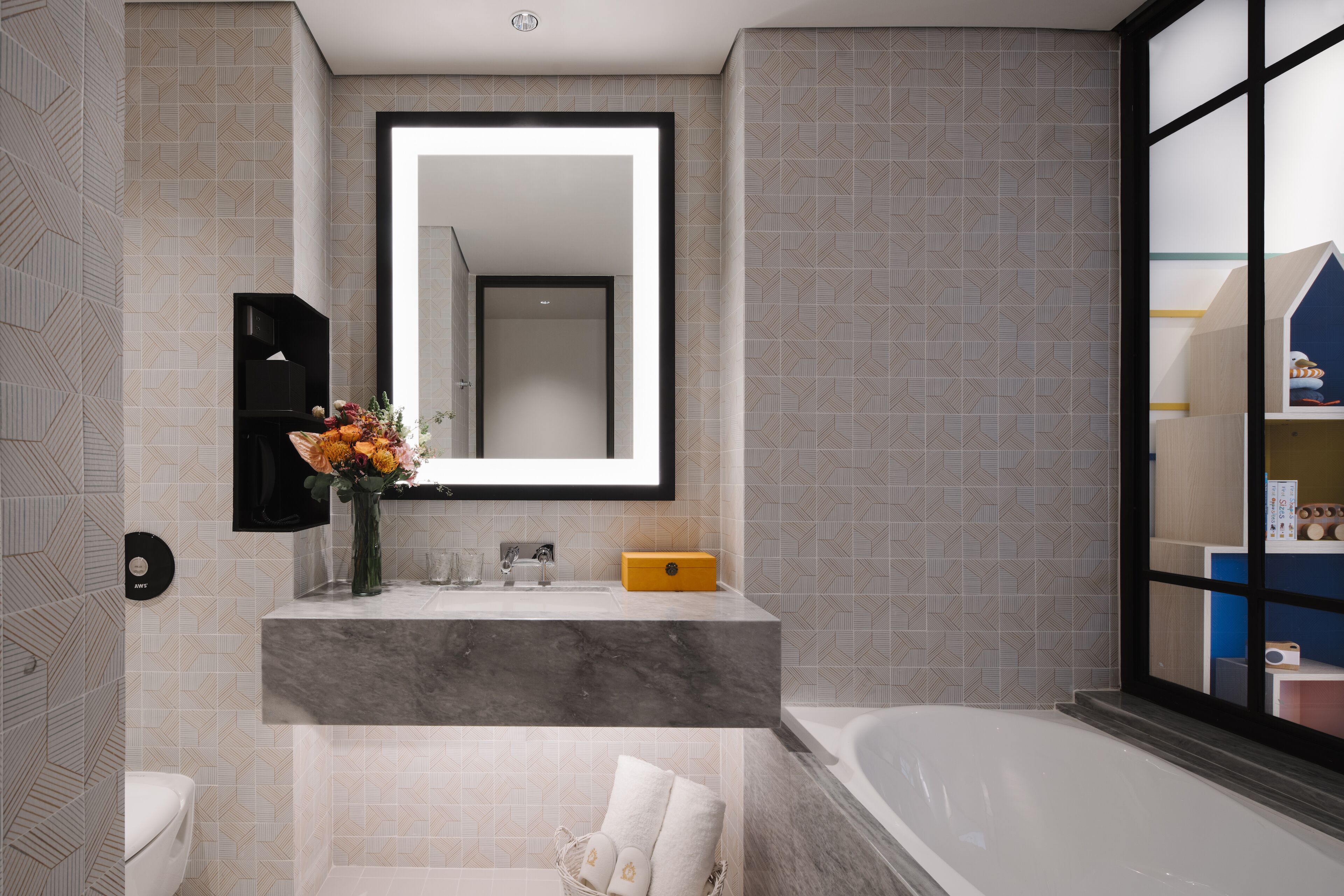 A modern bathroom with a marble sink, a large mirror, and a bathtub.