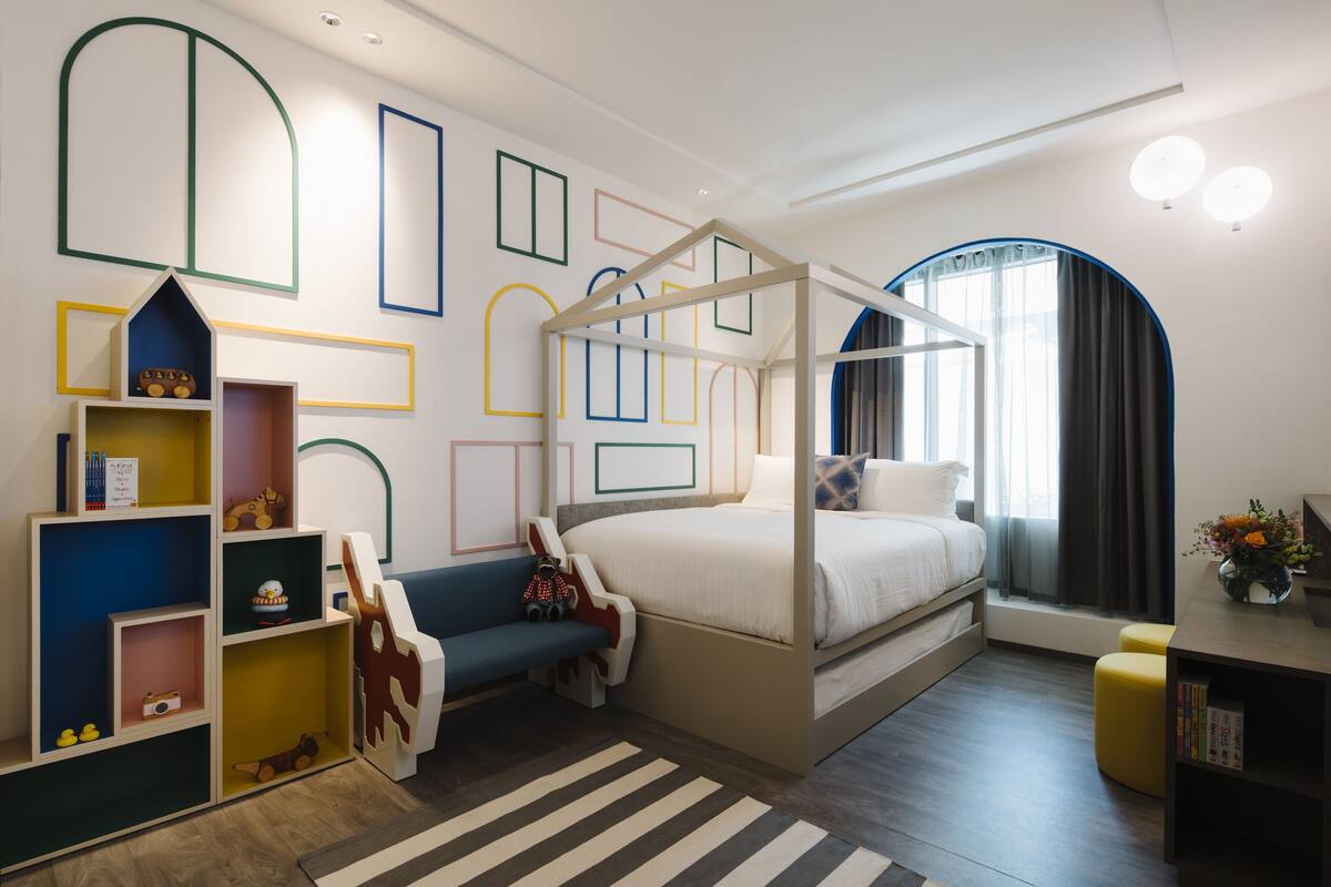 A modern bedroom with a canopy bed, built-in shelving, and a large window with curtains.