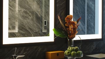 A modern bathroom with two mirrors, a black sink, and a vase with flowers.