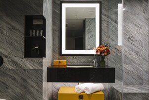 A modern bathroom with a black vanity, a mirror, and a yellow storage unit.