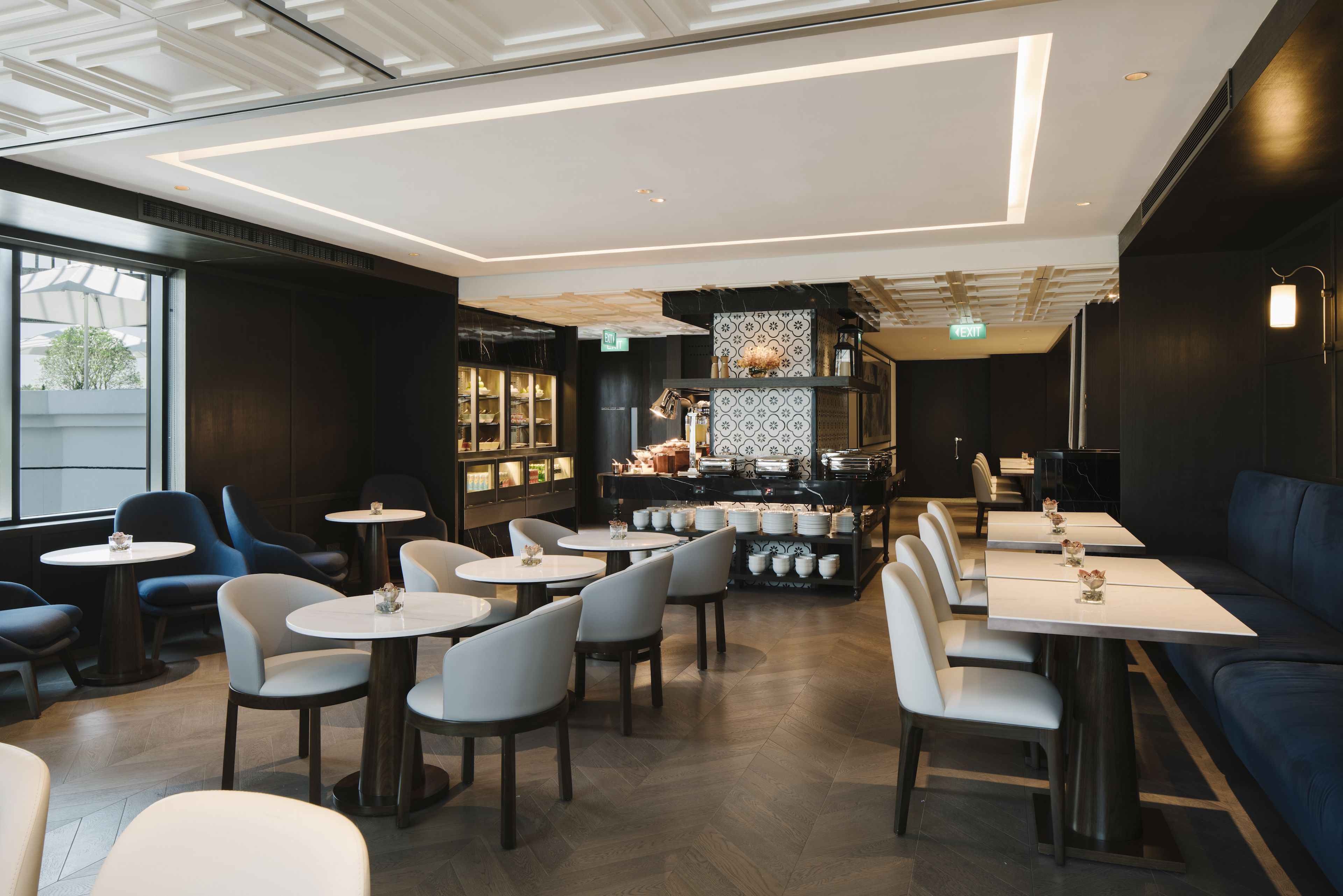 Un restaurant moderne avec des tables rondes, des chaises bleues et un coin bar.