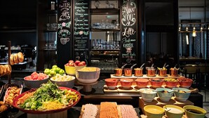 Un bufé con diversas opciones de comida y bebidas, como frutas, verduras, carnes y café.