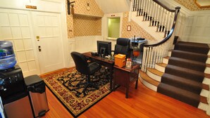A home office with a desk, computer, and chair, a water cooler, and a staircase. - Beacon Inn 1750 (Brookline)