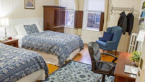 A hotel room with two beds, a chair, a desk, and a window with curtains. - Beacon Inn 1750 (Brookline)