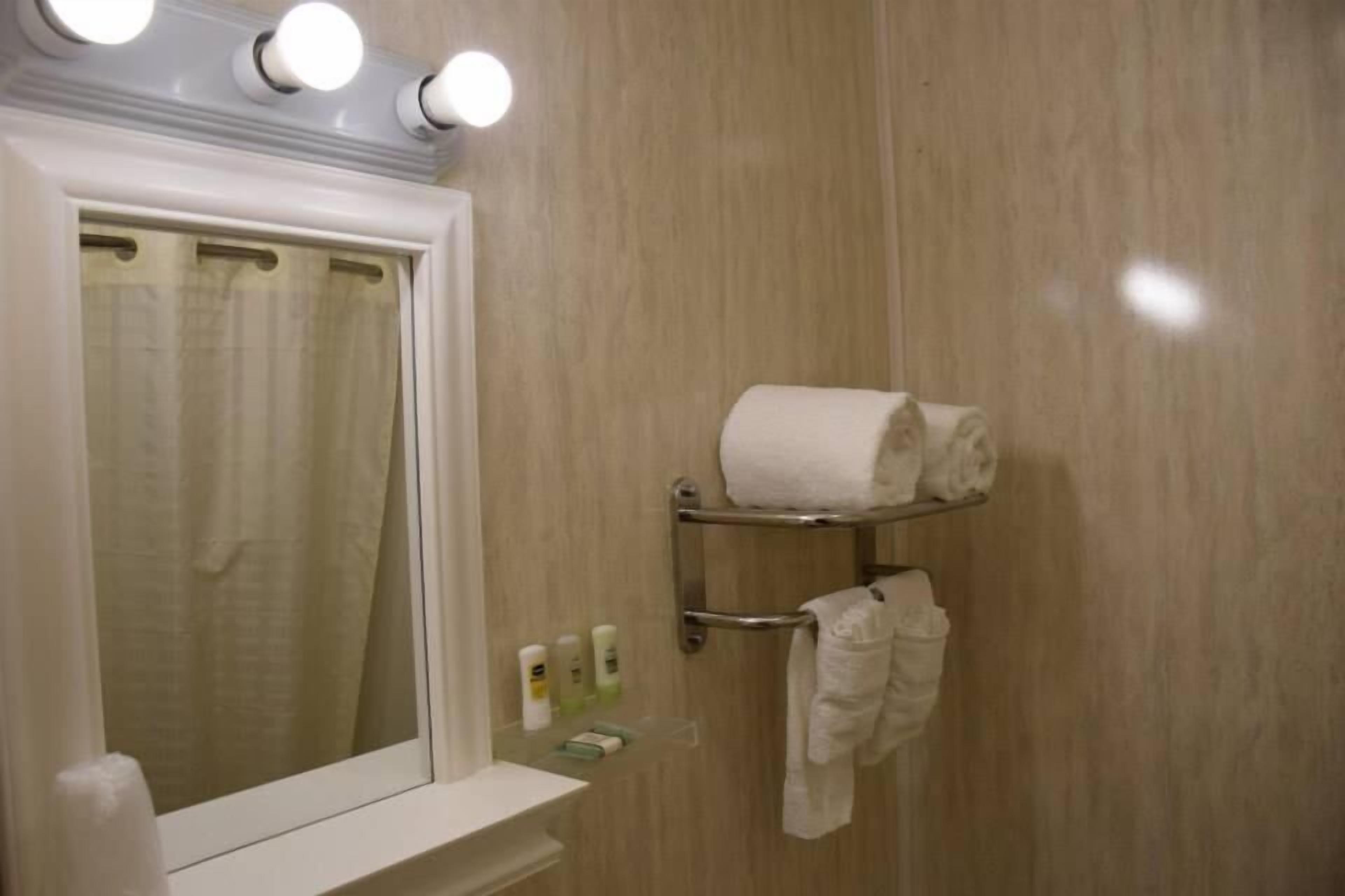 Une salle de bain équipée d’un miroir, d’un porte-serviettes et d’articles de toilette.