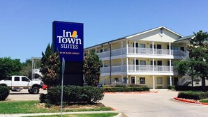 A hotel with a sign reading "In Town Suites" and a two-story building with balconies. - Intown Suites Extended Stay Select Houston - Stafford (Stafford)