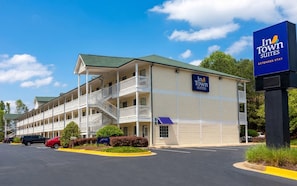 A two-story motel with a balcony on the second floor, a parking lot, and a sign for In Town Suites.