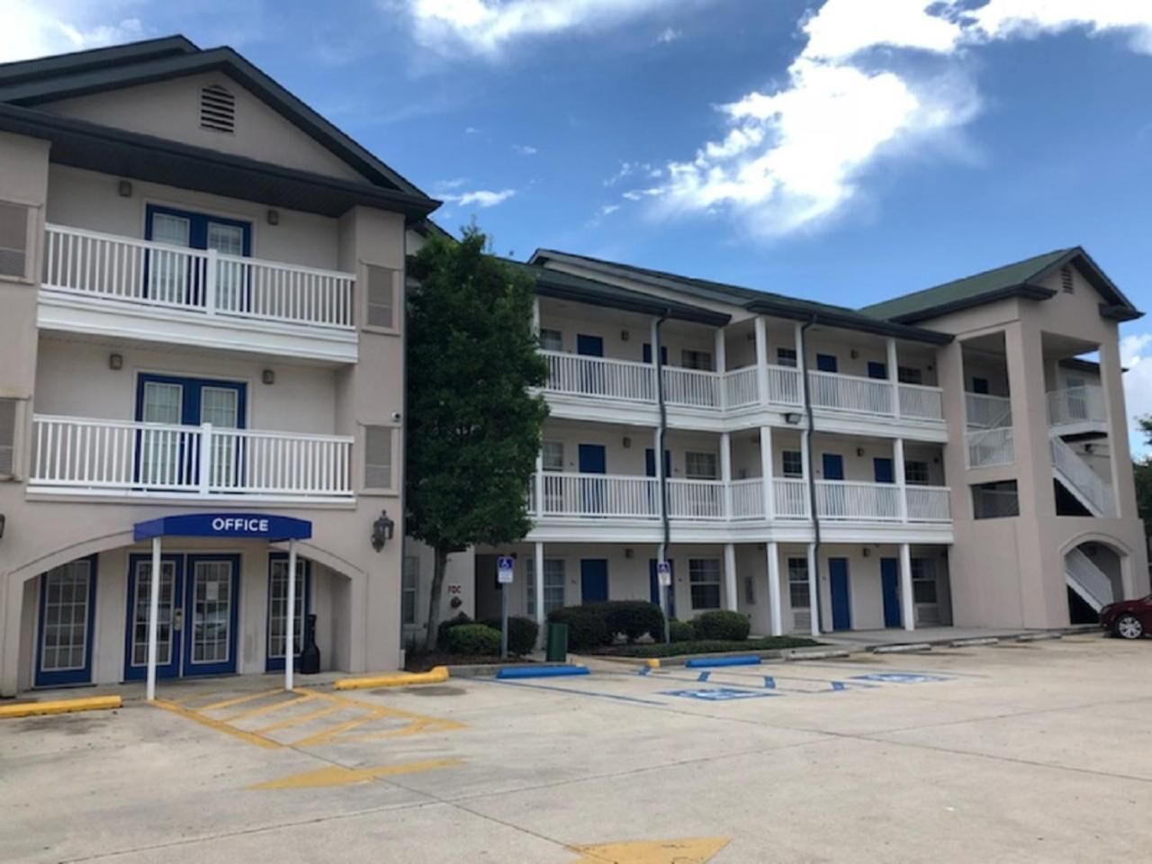 Um hotel com vários andares, um pátio central, varandas e um edifício de escritórios à esquerda.