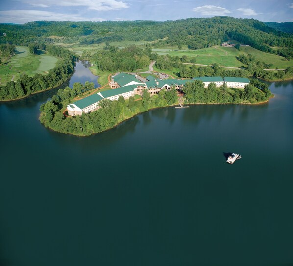 An aerial view of a lakeside resort with multiple buildings, a dock, and a boat.