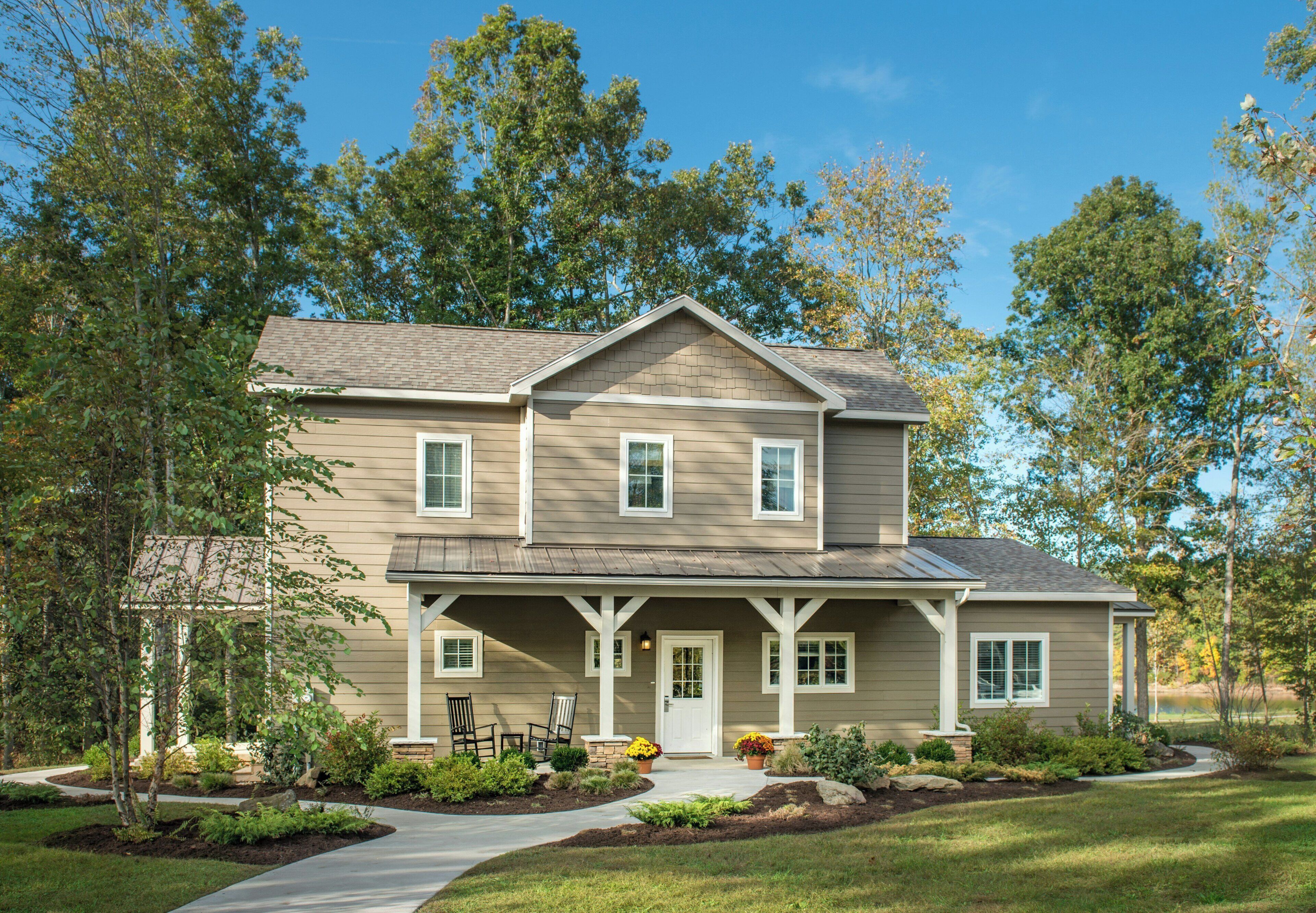 A two-story house with a front porch, a driveway, and a well-maintained lawn.