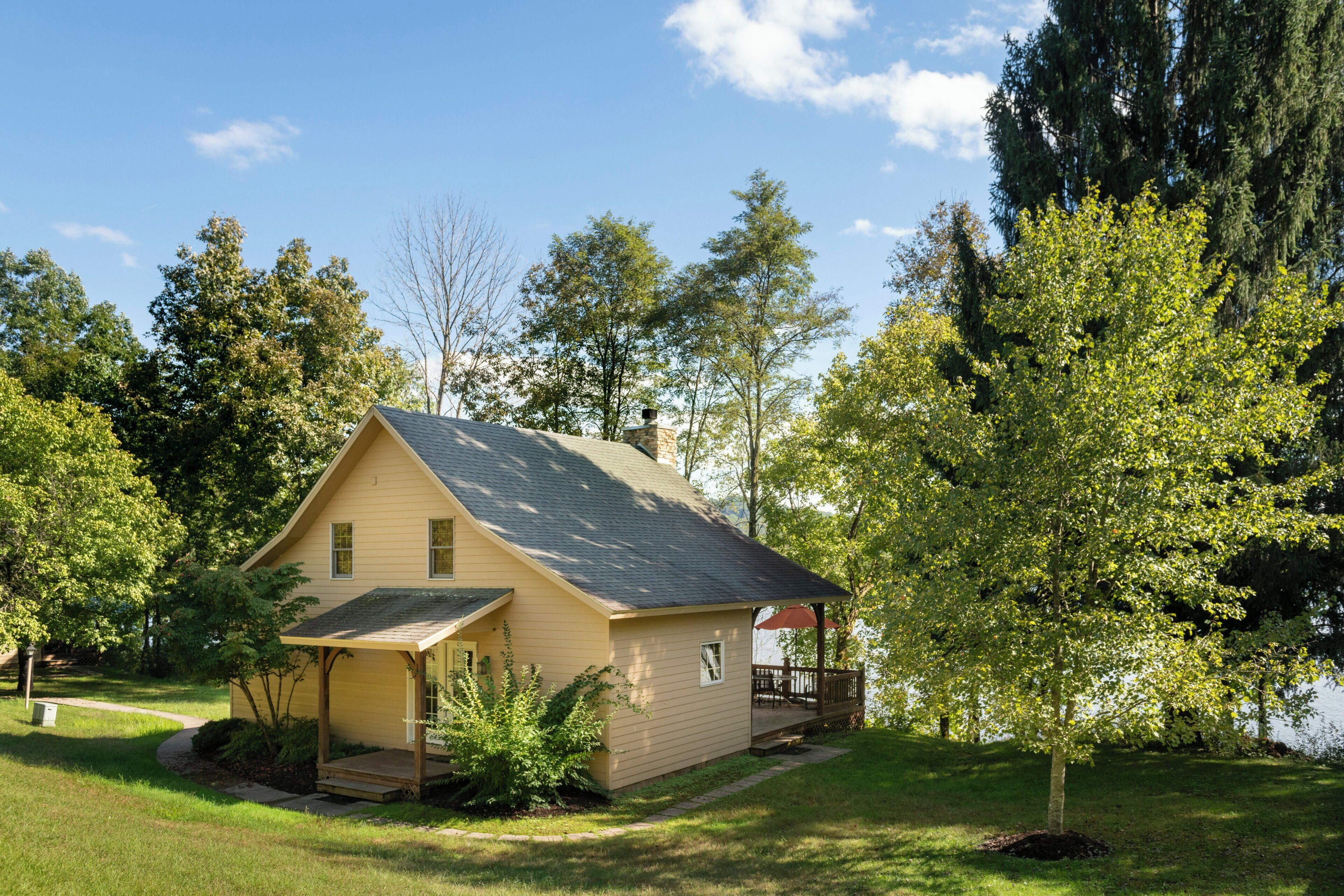 Ein einstöckiges Haus mit Veranda, umgeben von Bäumen und einem Rasen.