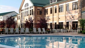 A swimming pool with lounge chairs and a building with a green roof and stone facade. - Stonewall Resort (Roanoke)