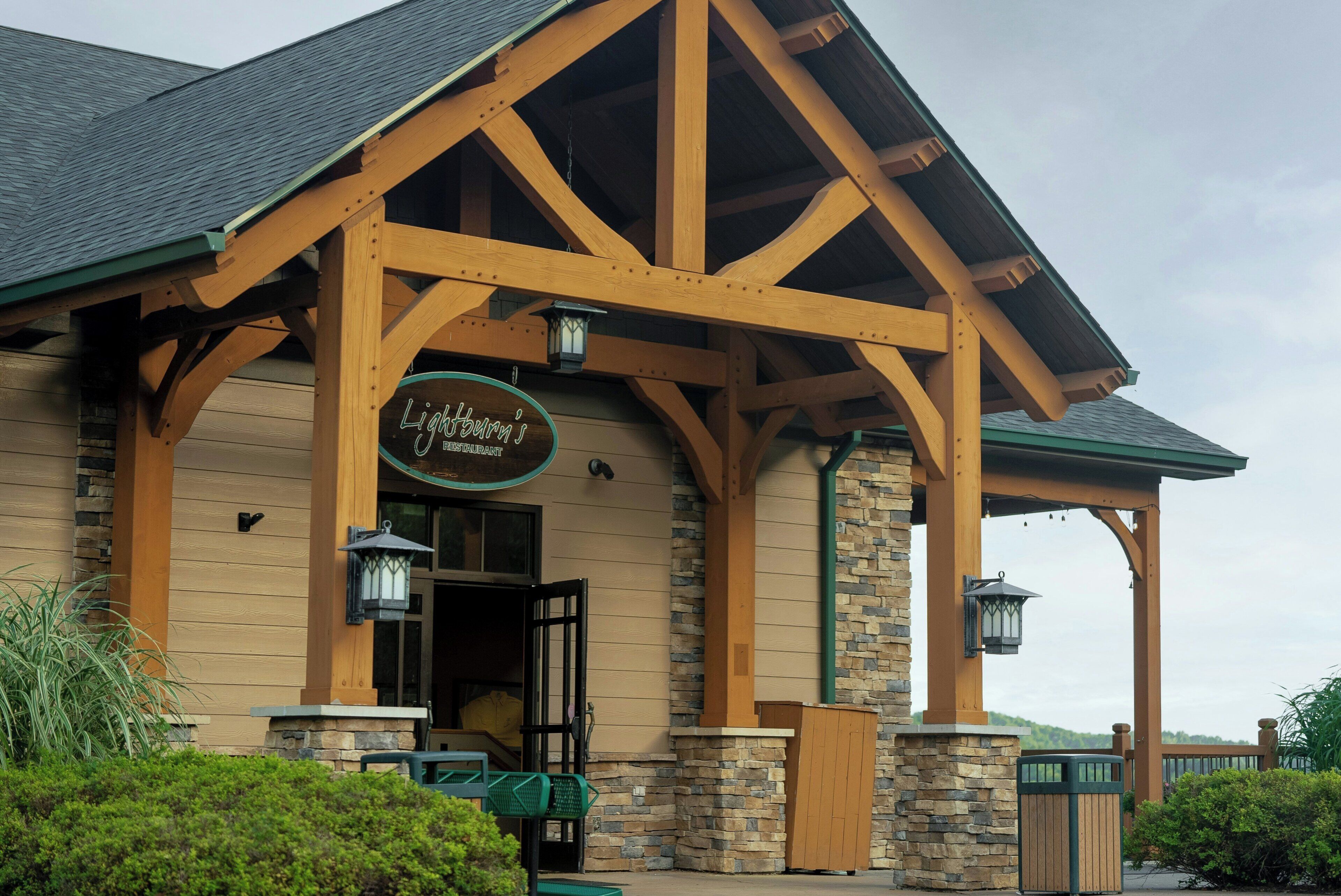 A restaurant with a wooden exterior and stone accents, featuring a signboard above the entrance.