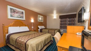 A hotel room with two beds, a wooden headboard, a desk, a chair, a television, and a painting on the wall.