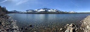 Un lac aux eaux limpides, bordé d’une rive rocheuse, avec une montagne en arrière-plan.