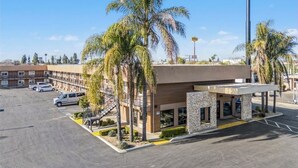 A Days Inn hotel with a parking lot, palm trees, and a clear sky.