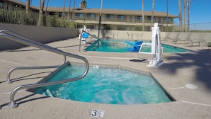 A pool area with a 3½ ft depth marker, lounge chairs, and palm trees. - Americas Best Value Inn Blythe (Blythe)