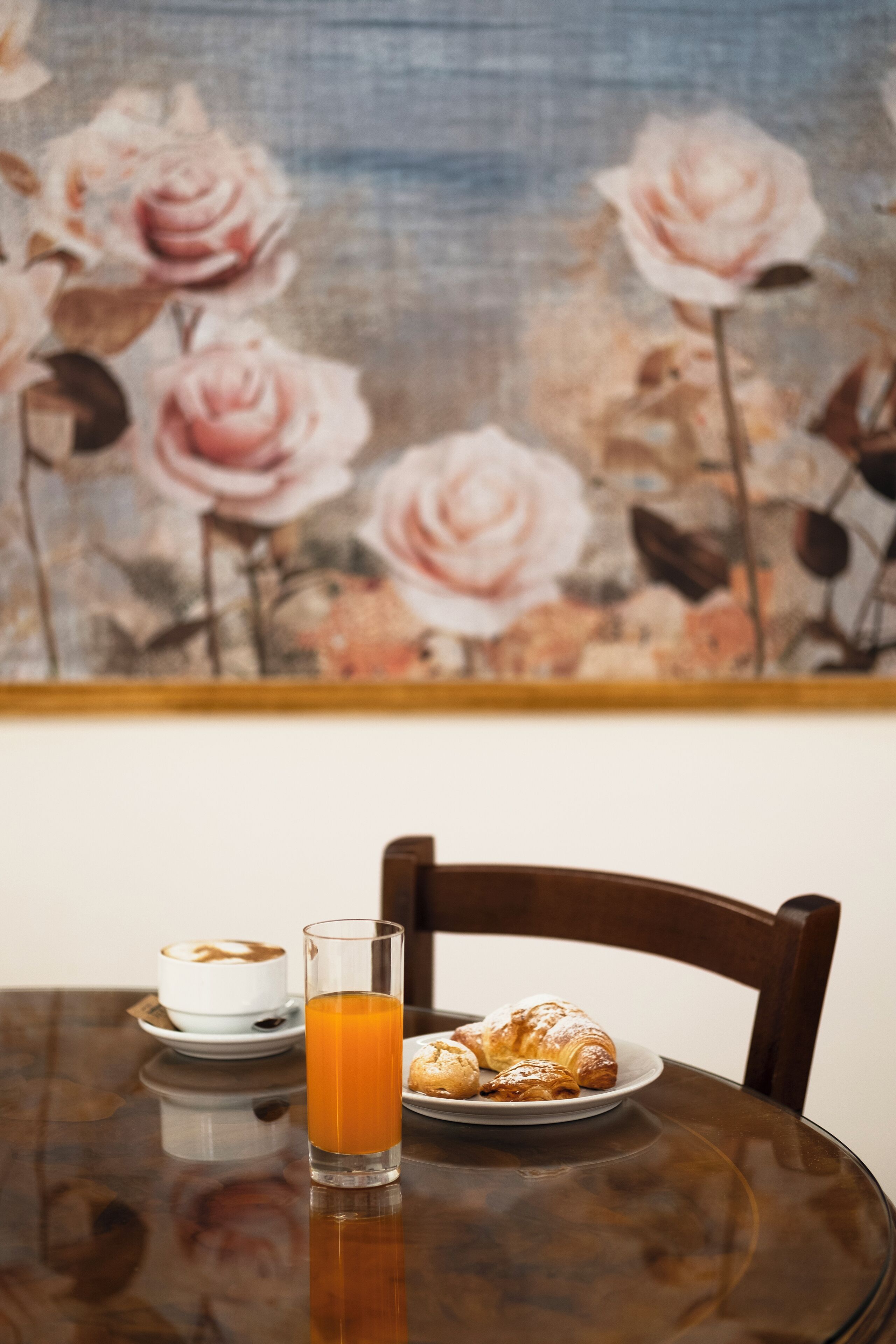 Ein Esstisch mit einem Glas Orangensaft, einer Tellerr voller Croissants und einer Tasse Kaffee.