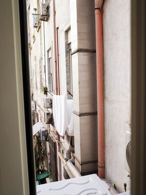 A narrow urban street with buildings, visible pipes, and a fan. - Grand Hotel Europa (Naples)