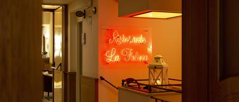 A hallway with a neon sign reading "Ristorante La Fulgora" and a lantern on a railing.