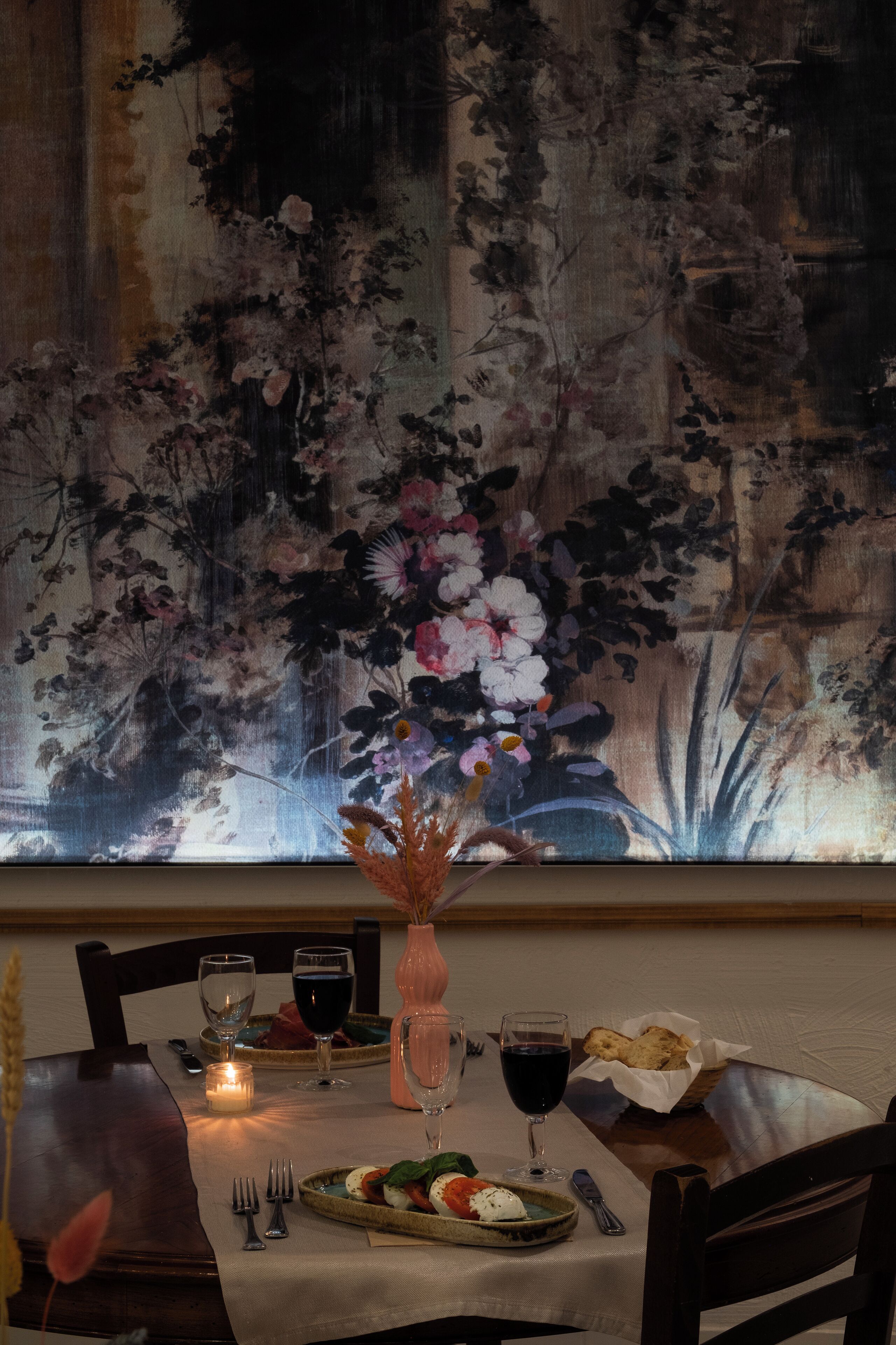 A dining table set with a candle, wine glasses, and a plate of food.