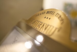 Primer plano de un objeto metálico con texto grabado que dice "GRAND HOTEL EXPO" y "PALENUIP".