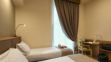 A hotel room with two beds, a desk, a chair, and a window with curtains.