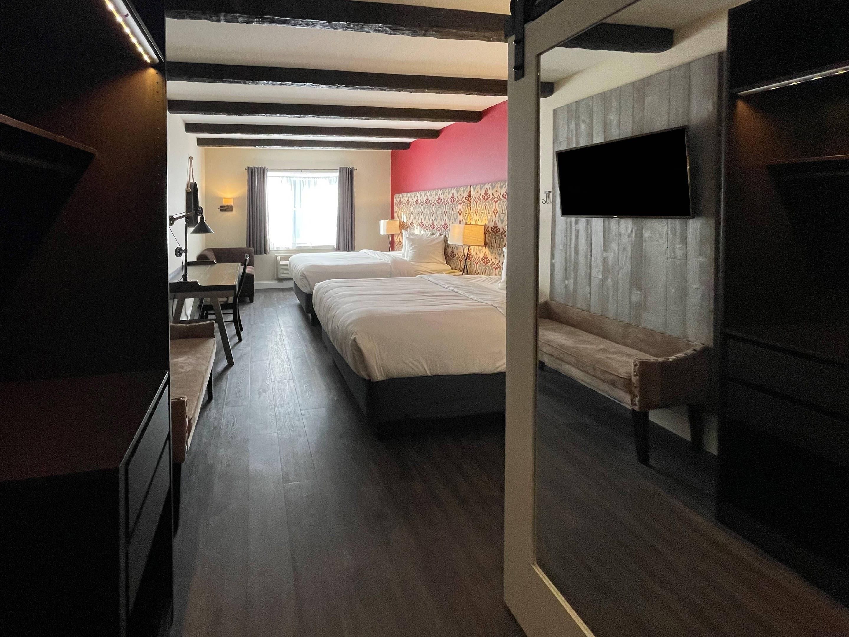 Habitación de hotel con una cama grande, un escritorio, una silla, un televisor y una ventana con cortinas.