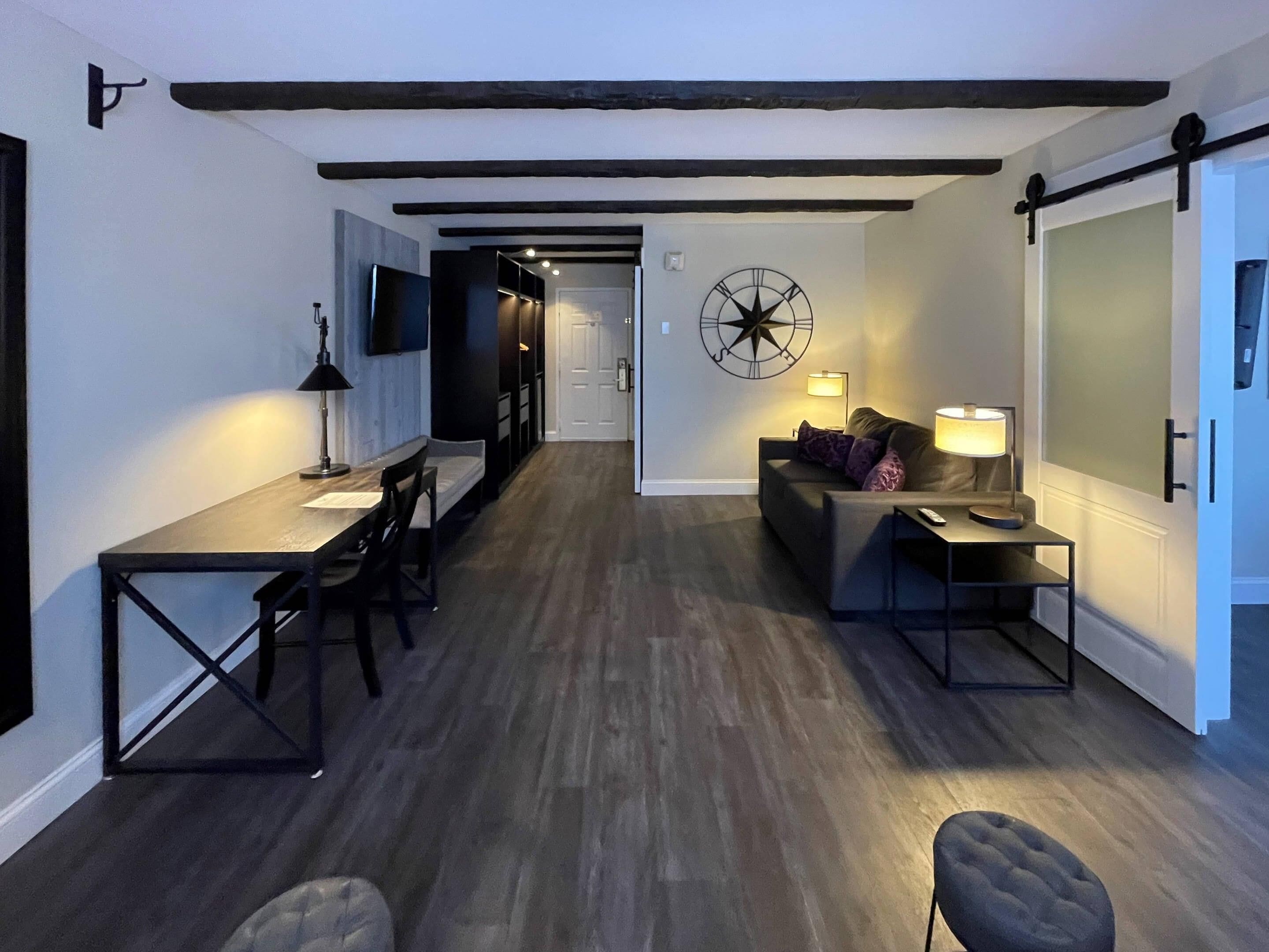 A modern interior with a dining area, a sofa, and a wall-mounted clock.
